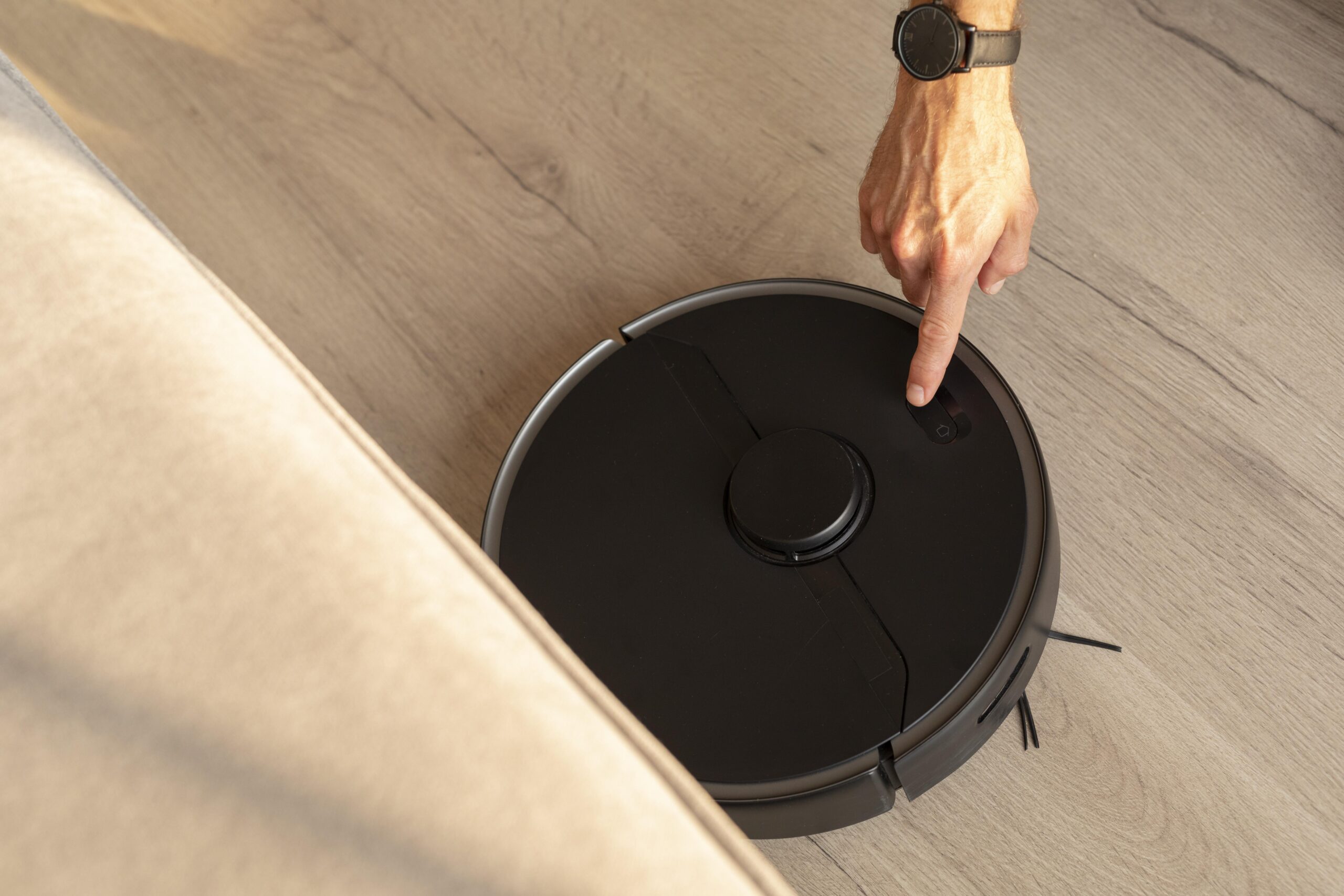 man-using-robot-vacuum-living-room man-using-robot-vacuum-living-room